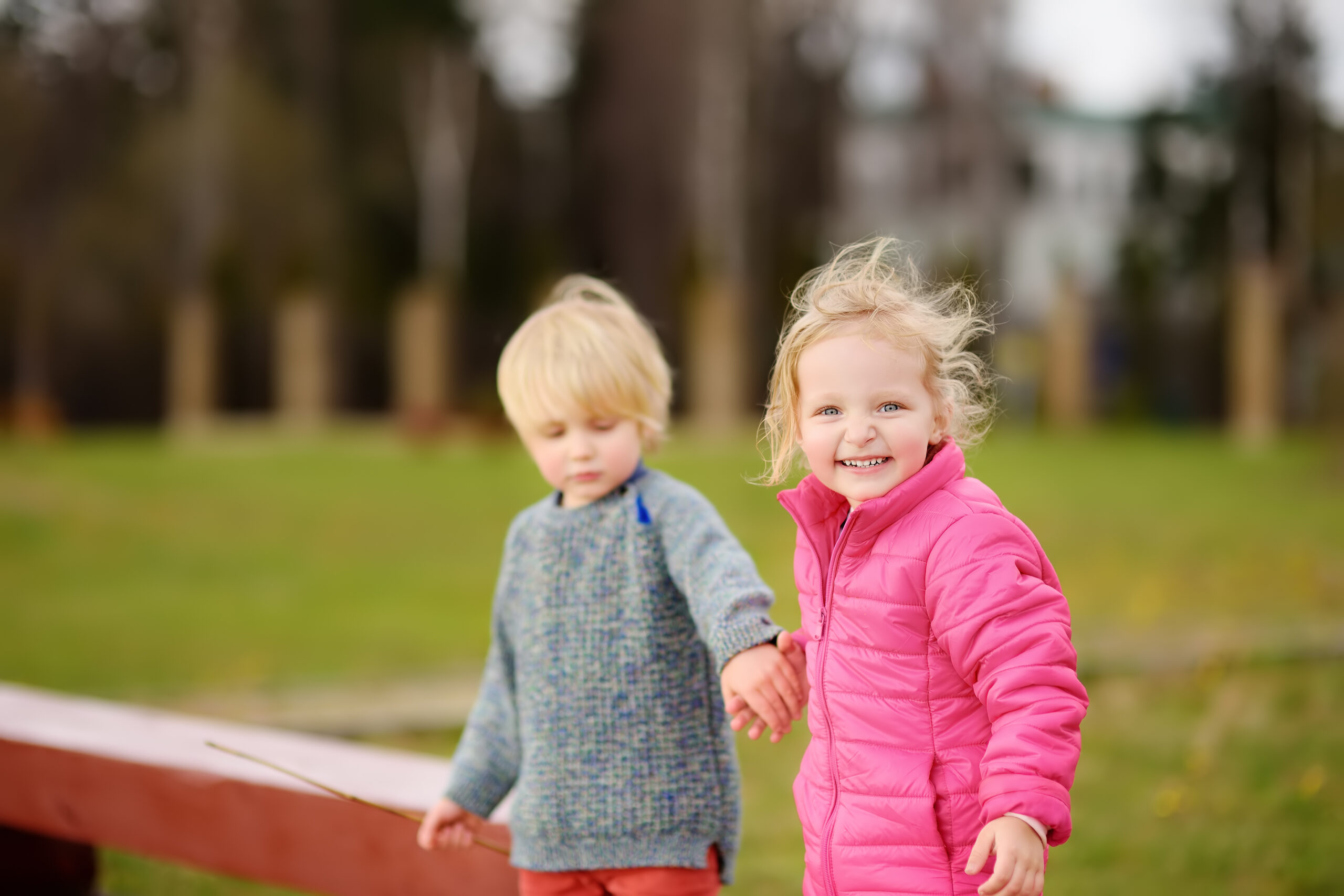 Happy kids having fun. Spring/summer/autumn outdoor active leisure for children. Portrait of little boy and girl playing on kindergarten back yard